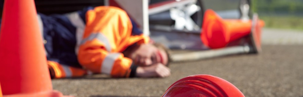 Man with a head injury laying on a road wearing PPE